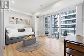 Kitchener condo for rent - A bedroom with a large bed and a balcony with a chair.