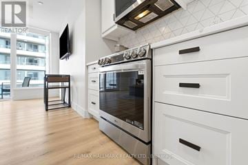 Kitchener condo for rent - A modern kitchen with a stainless steel oven and white cabinets.
