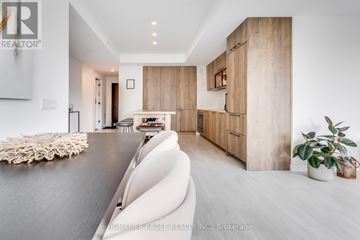 Toronto (Waterfront Communities) condo for rent - A modern living room with a white sofa and wooden cabinets.