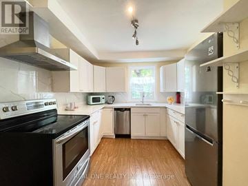 Waterloo townhouse for rent - A kitchen with white cabinets and black appliances.