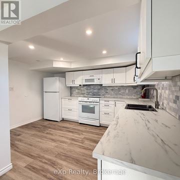 Quinte West (Trenton Ward) apartment for rent - A kitchen with white appliances and a marble countertop.