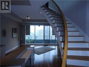 Toronto (Bay Street Corridor) condo for rent - A wooden staircase with a metal railing leads to a balcony.