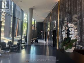 Toronto (Waterfront Communities) condo for rent - A lobby with a large glass wall and a flower vase on a table.