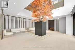Mississauga (City Centre) condo for rent - A tree with orange leaves is in a room with a white ceiling and a white couch.