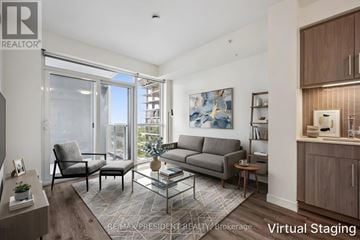 Burlington (Freeman) condo for rent - A living room with a grey sofa, a glass table, and a painting on the wall.