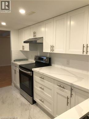 Hamilton apartment for rent - A modern kitchen with white cabinets and a black stove top oven.