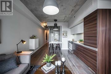 Toronto (Little Portugal) condo for rent - A modern living room with a grey sofa and a wooden floor.