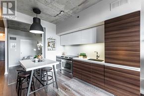 Toronto (Little Portugal) condo for rent - A modern kitchen with a white table and bar stools.