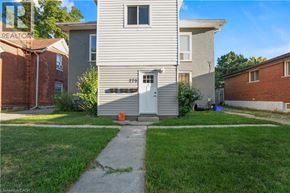 Brantford apartment for rent - A house with a grey facade and a white door is surrounded by a green lawn.