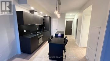 Toronto (Waterfront Communities) condo for rent - A modern kitchen with a dining table and chairs.