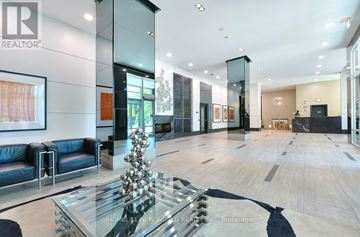 Toronto (Willowdale East) condo for rent - A modern living room with a glass table and a black leather couch.
