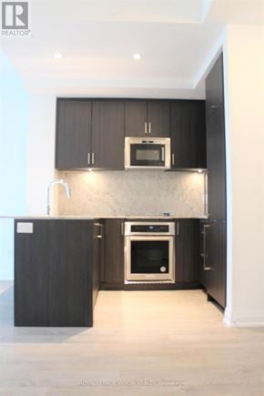 Toronto (Annex) condo for rent - A modern kitchen with dark wood cabinets and stainless steel appliances.