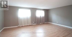 London North (North N) fourplex for rent - A room with wooden flooring and two windows with curtains.