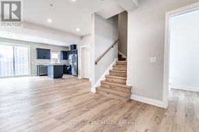 St. Catharines (Oakdale) townhouse for rent - A spacious room with wooden floors and a staircase leading to another level.