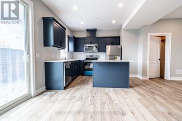 St. Catharines (Oakdale) townhouse for rent - A modern kitchen with dark blue cabinets and a wooden floor.