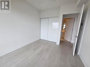 Toronto (Bayview Village) condo for rent - A room with white walls and a grey floor with a door open to another room.