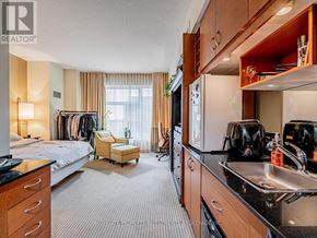 Toronto (Bay Street Corridor) condo for rent - A well-lit hotel room with a bed, chair, and kitchenette.