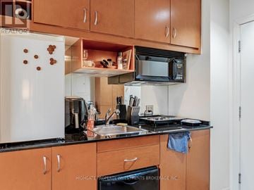 Toronto (Bay Street Corridor) condo for rent - A kitchen with wooden cabinets and a white refrigerator.