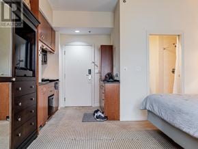 Toronto (Bay Street Corridor) condo for rent - A bedroom with a bed, dresser, and a small kitchenette.