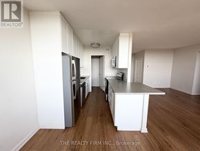 London East (East B) condo for rent - A kitchen with white cabinets and a wooden floor.