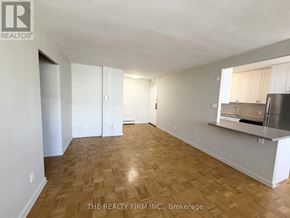 London East (East B) condo for rent - A spacious room with wooden flooring and white walls, with a kitchenette in the corner.