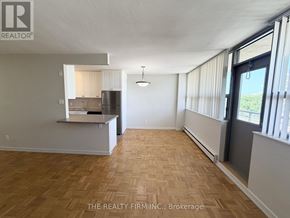 London East (East B) condo for rent - A room with wooden flooring and a kitchen area with white cabinets.