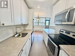 London East (East B) condo for rent - A kitchen with white cabinets and a black stove top oven.