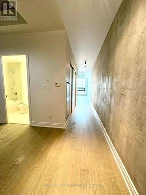 Toronto (Waterfront Communities) condo for rent - A long hallway with wood floors and white walls.