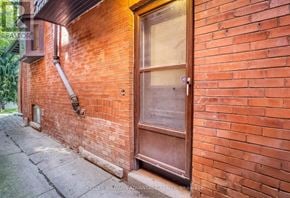 Toronto (Annex) apartment for rent - A red brick wall with a door and a window.
