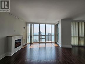 Toronto (Waterfront Communities) condo for rent - A spacious room with a fireplace and large windows overlooking the city.