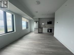 Vaughan (Concord) condo for rent - A spacious, empty room with a kitchenette and large windows.