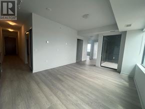 Vaughan (Concord) condo for rent - A spacious room with wooden flooring and white walls, with a door on the left and a window on the right.