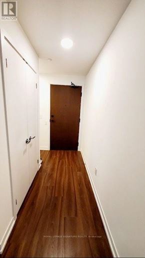Mississauga (City Centre) condo for rent - A long hallway with a brown door at the end.