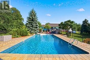 Prince Edward County (Ameliasburg Ward) apartment for rent - A pool surrounded by trees and a house in the background.