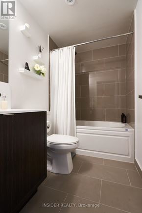 Toronto (Waterfront Communities) condo for rent - A white toilet sits next to a white bathtub in a bathroom.