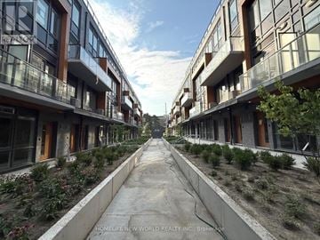 Toronto (Parkwoods-Donalda) townhouse for rent - A long, narrow walkway separates two rows of modern townhouses.