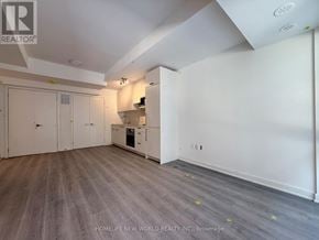 Toronto (Parkwoods-Donalda) townhouse for rent - A spacious room with a kitchenette and wooden flooring.