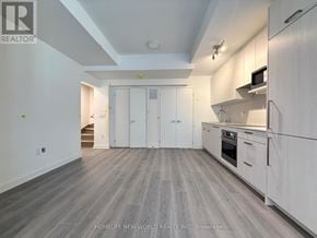 Toronto (Parkwoods-Donalda) townhouse for rent - A spacious kitchen with white cabinets and a grey floor.