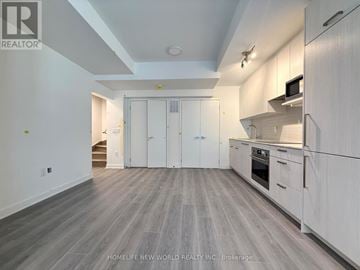 Toronto (Parkwoods-Donalda) townhouse for rent - A spacious kitchen with white cabinets and a grey floor.