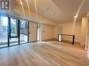 Toronto (Moss Park) townhouse for rent - A spacious room with wooden flooring and a large window with a view of a city street.