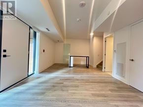 Toronto (Moss Park) townhouse for rent - A spacious room with wood flooring and white walls.