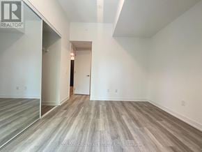 Toronto (Moss Park) townhouse for rent - A spacious room with wood flooring and white walls, part of a real estate listing.