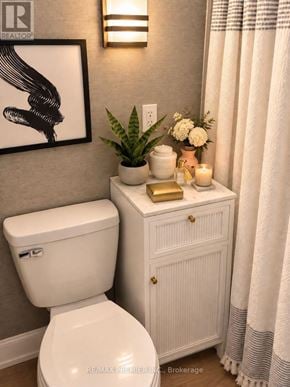 Oakville (Wo West) apartment for rent - A white toilet sits next to a white cabinet with a plant on top.