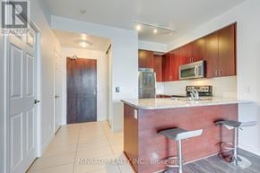 Mississauga (City Centre) condo for rent - A kitchen with a bar stool and a fridge.