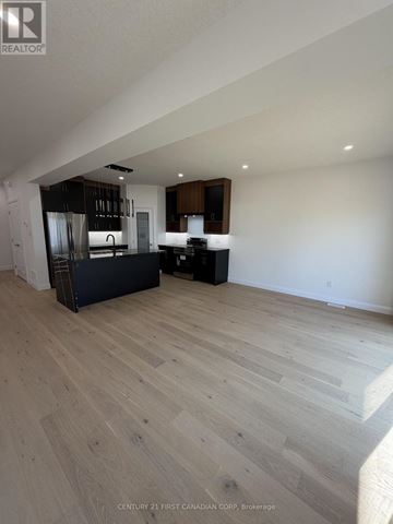 London South (South U) apartment for rent - A spacious room with wooden flooring and a kitchen area in the background.