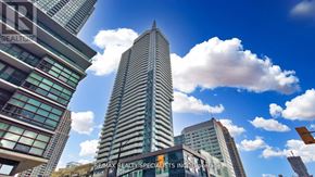 Mississauga (City Centre) condo for rent - A tall skyscraper stands in the center of a cityscape with other buildings around it.