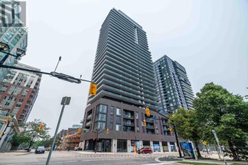 Burlington (Brant) condo for rent - A modern building with a glass facade stands tall in a cityscape.