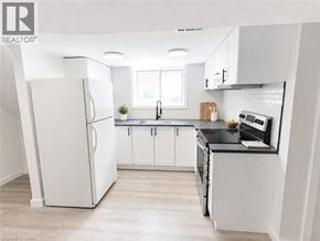 Hamilton apartment for rent - A white refrigerator stands in a kitchen with white cabinets and a black countertop.