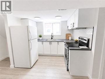 Hamilton apartment for rent - A white refrigerator stands in a kitchen with white cabinets and a black countertop.