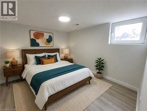 Hamilton apartment for rent - A bedroom with a bed, two lamps, a plant, and a painting on the wall.